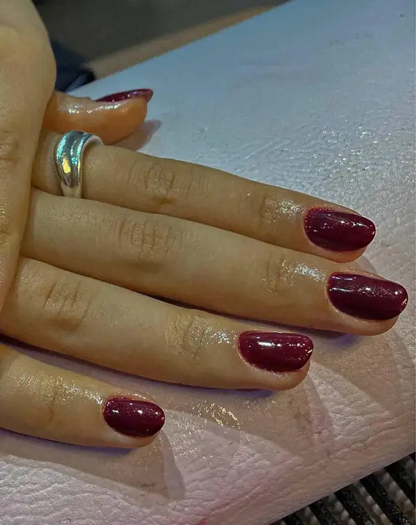 Unhas em esmalte vermelho escuro